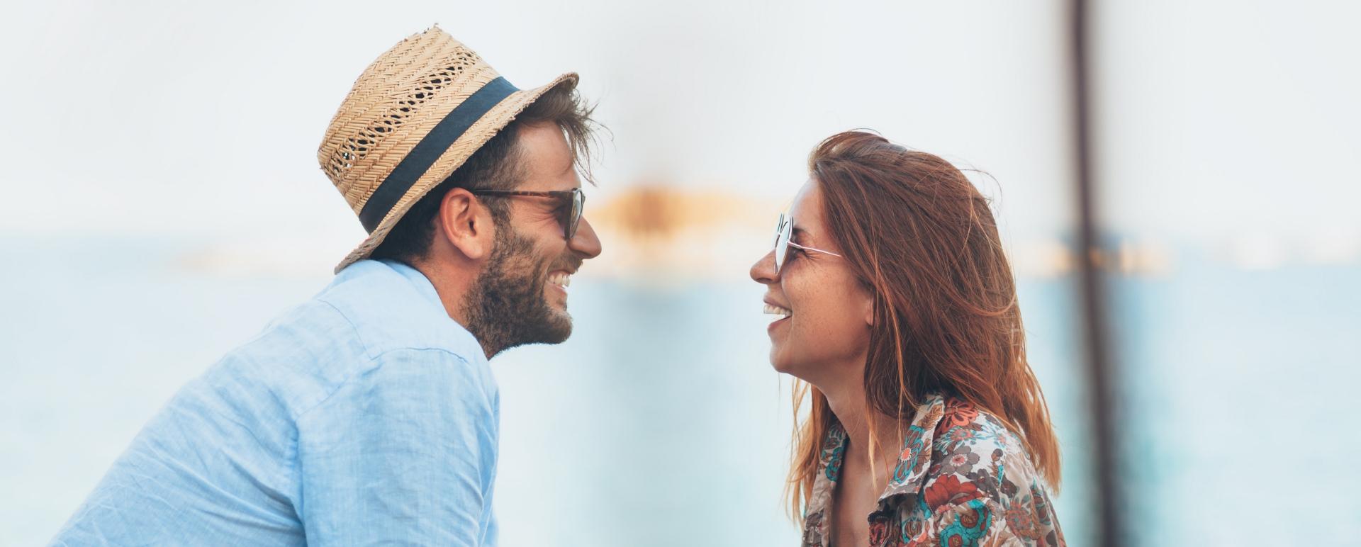 Madre e figlio sorridenti scattano un selfie al sole, indossando cappelli di paglia.