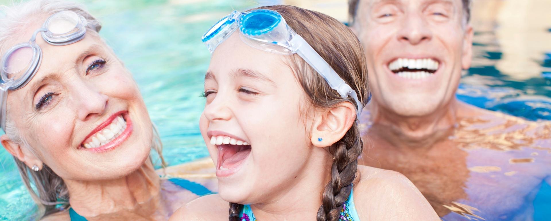 Famiglia felice in piscina con occhiali da sole e ciambella gonfiabile.