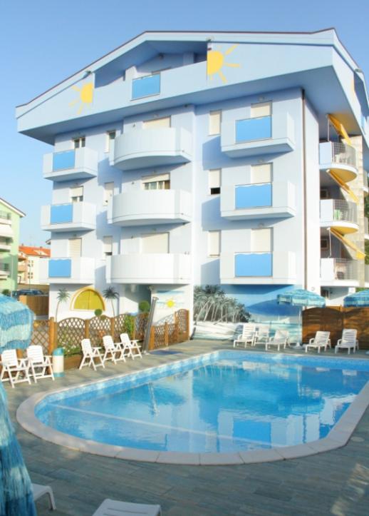 Moderno edificio blu con piscina e sdraio, decorazioni solari e palme.